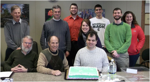 ATC members posing behind cake. Standing: Ries, Hudson, Smeltekop, Sebald, Moul, Pierce, Roe. Seated: White, Blosser, Puzzuoli.